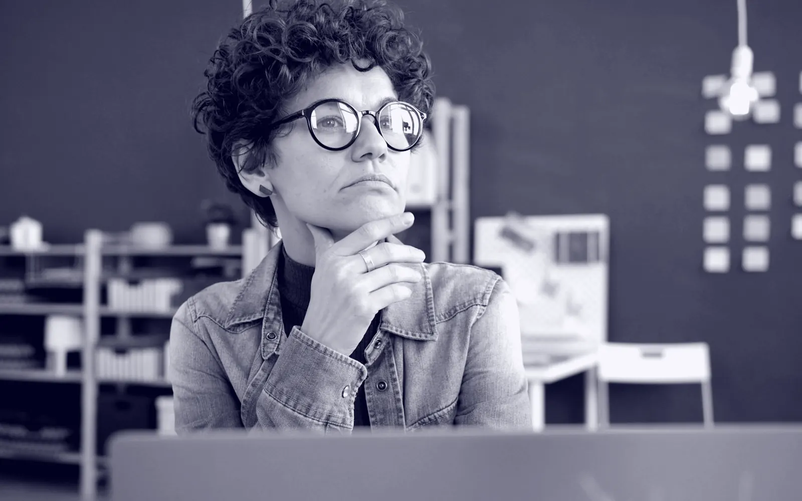 Una persona con gafas reflexiona frente a su escritorio